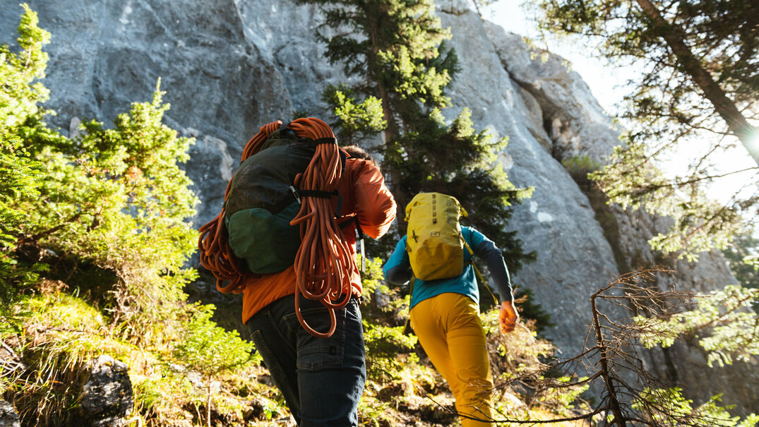Zwei Kletterer wandern durch einen Wald zur Grauwand