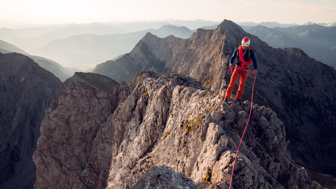 Ein Kletter auf der Lamsenspitze über vor einer atemberaubenden Bergkette bei schönem Wetter.