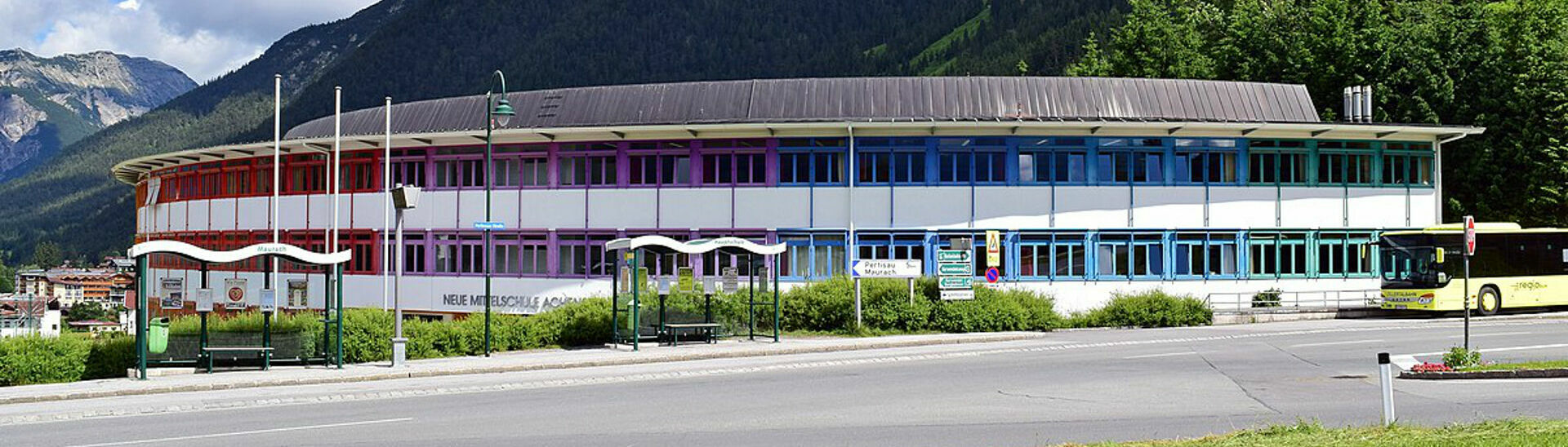 Das farbenfrohe Gebäude der Hauptschule Achensee in Maurach mit der Rotspitze im Hintergrund.