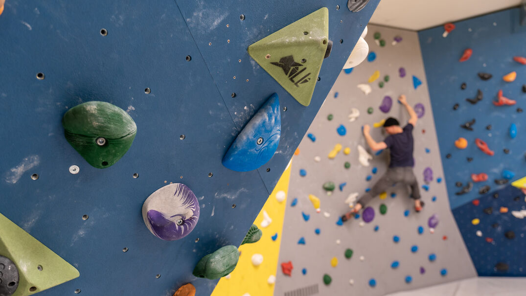 Ein Mann begibt sich in die Vertikale in der BOULDER-Halle im Atoll Achensee in Maurach.