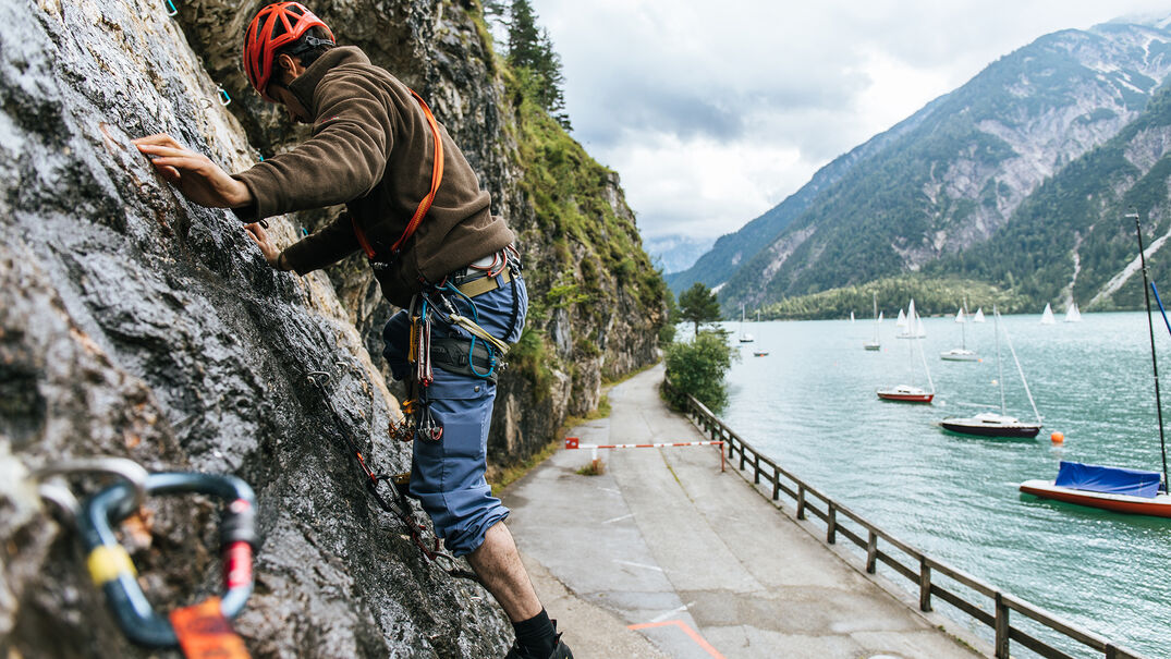 Klettern am Achenseehof in Achenkirch Ein Mann der gerade die Kletterwand am Achenseehof neben dem schönem Achensee besteigt.