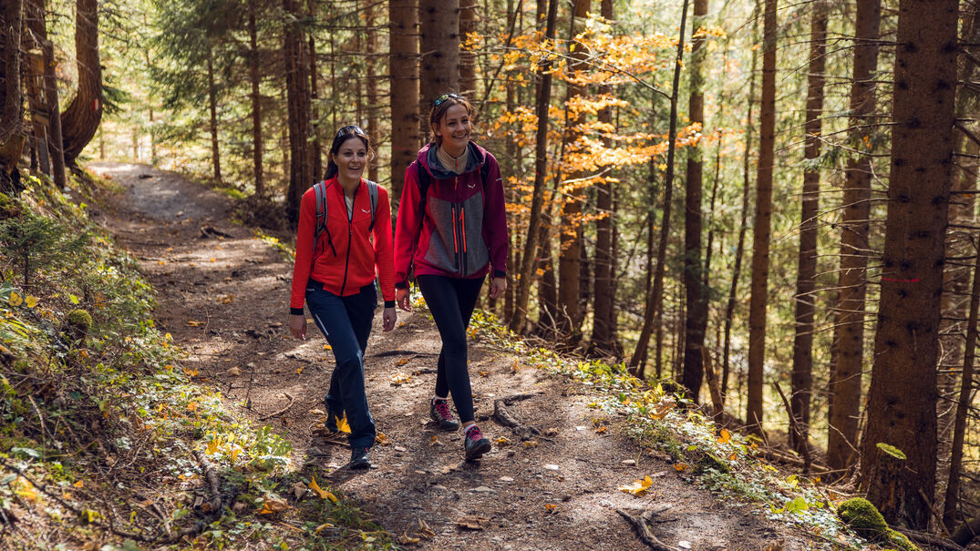 Zwei Freundinnen wandern im Herbst den Tunnelweg entlang in Richtung Zwölferkopf und lassen sich von der beeindruckenden Aussicht verzaubern.
