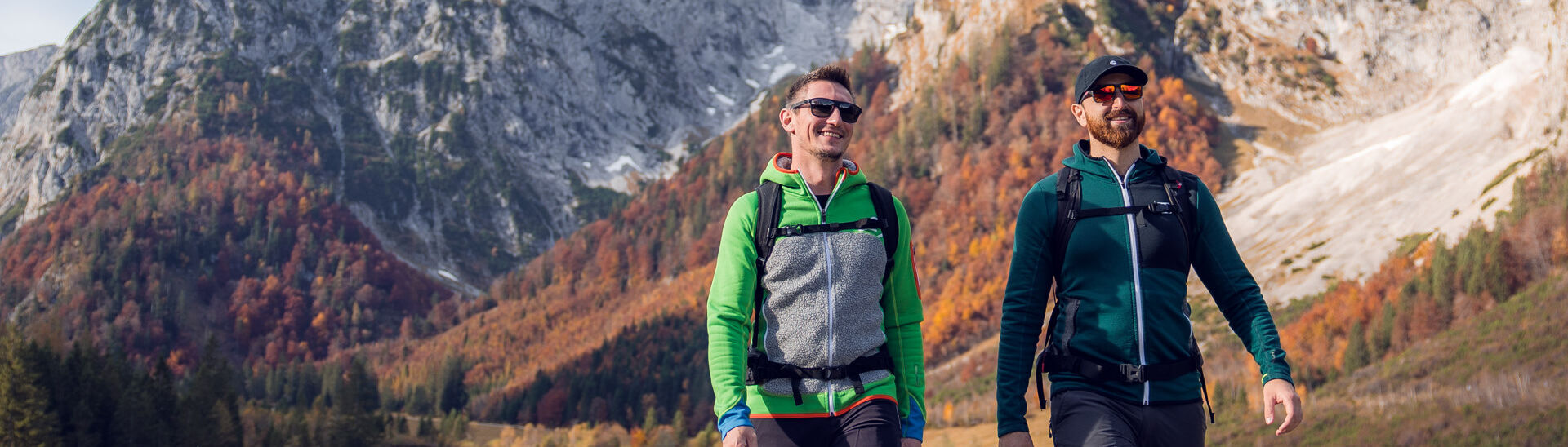 Zwei Wanderer nutzen das herrliche Wetter und unternehmen eine Herbstwanderung durch das farbenfrohe Falzthurntal im Naturpark Karwendel. Im Bild ragt das Sonnjoch markant empor.