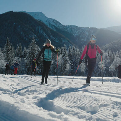 Eine Frau nimmt bei herrlichem Wetter am Achensee Langlaufcamp (Klassisch) in den verschneiten Karwendeltälern teil.
