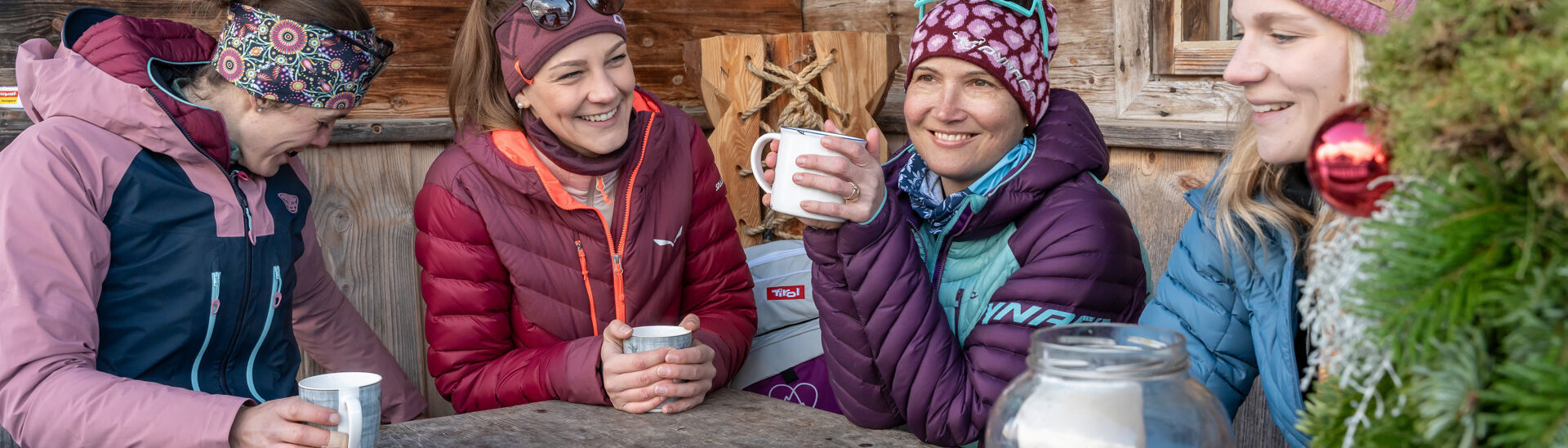 Eine Gruppe von Freundinnen genießt Tee und eine kleine Brettljause auf der Terrasse einer Hütte.