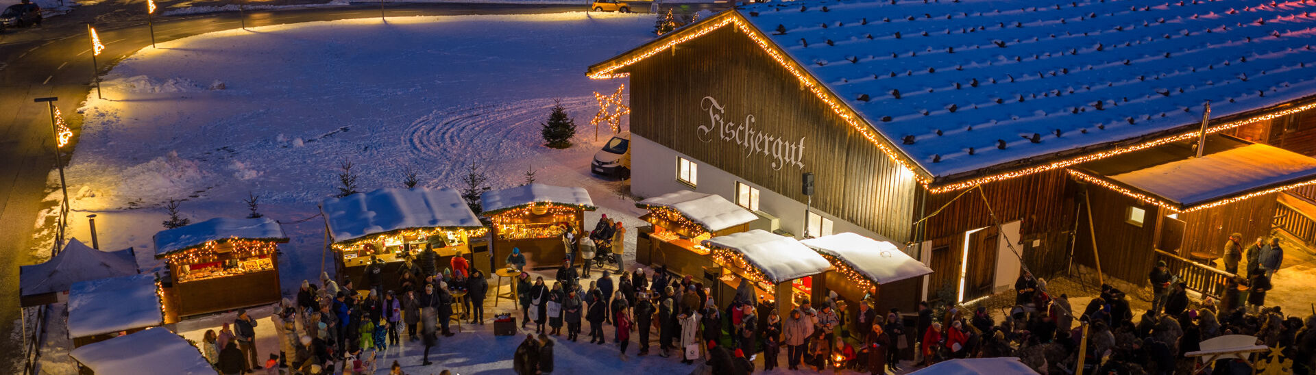 The Christmas market at Fischergut sparkles with lights and is surrounded by snow. Many visitors enjoy spending time there during the pre-Christmas season.