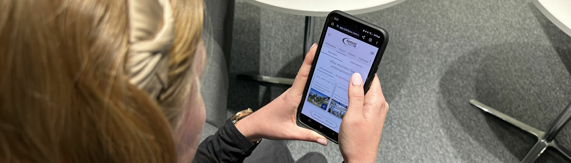 Eine Frau entdeckt den digitalen Urlaubsbegleiter my Achensee auf ihrem Handy.