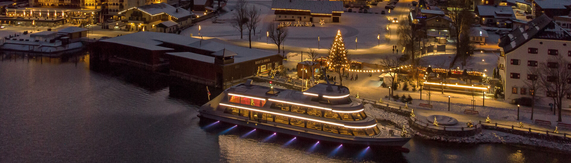 Die mit Schnee bedeckte Ortschaft Pertisau am Achensee wird in der Adventzeit wunderschön beleuchtet bei Nacht.