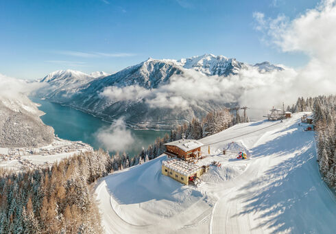 Blick auf die Karwendel-Bergbahn im Winter mit dem Alpengasthaus Karwendel und dem Achensee.