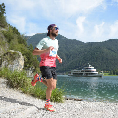 Ein Teilnehmer auf der Trail-Strecke des Achenseelaufs. Im Hintergrund ist die Achenseeschifffahrt zu sehen.
