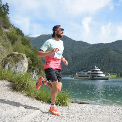 A participant on the trail route of the Achensee Run. The Achensee boat service can be seen in the background.