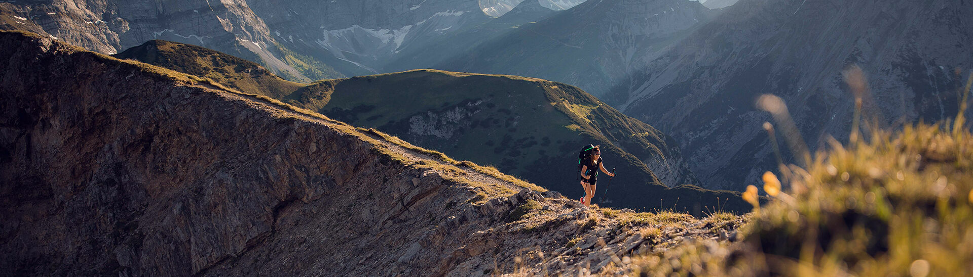 Eine Frau auf dem Weg zum Gipfel vom Sonnjoch bei blauem Himmel.