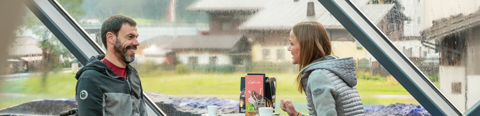 Two friends chat over a hot drink at Café Vitalberg. The bar is accessible barrier-free via the panoramic lift.