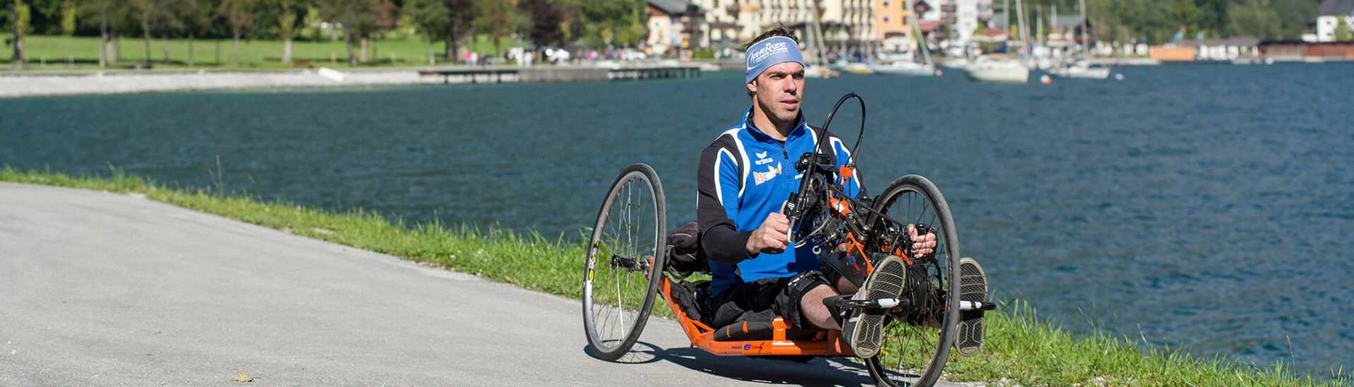 Ein Mann radelt mit seinem Handbike die barrierefreie Route entlang des Achenseeufers in Pertisau.