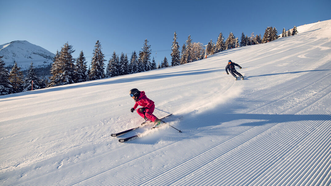 Bei strahlendem Wetter genießen zwei Skifahrer ihren Tag bei den Hochalmliften Christlum in Achenkirch am Achensee.