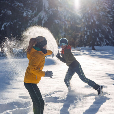Zwei Geschwister toben im frisch gefallenen Neuschnee und genießen bei strahlendem Wetter die gemeinsame Zeit in den Karwendeltälern.