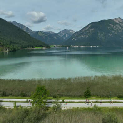 Teilnehmer laufen auf der Achenseelauf-Strecke mit Blick auf den See.
