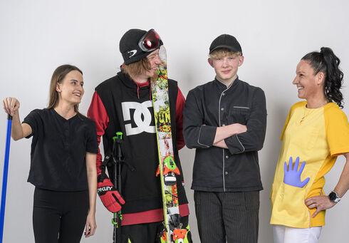 Ein Zimmermädchen, ein Skifahrer, ein Kochlehrling & eine Pflegerin posieren vor der Kamera.