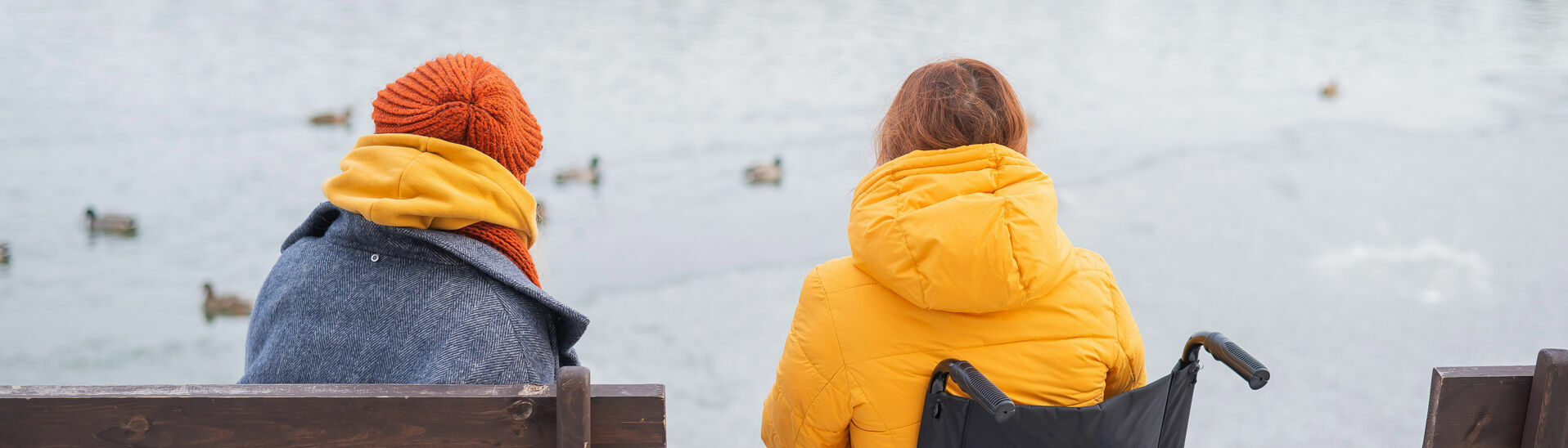 Barrierefreier Familienurlaub am Achensee Eine kleine Familie aus einer Rollstuhlfahrerin und einer Frau genießen die Aussicht auf den leicht gefrorener See und dessen winterliche Umgebung.