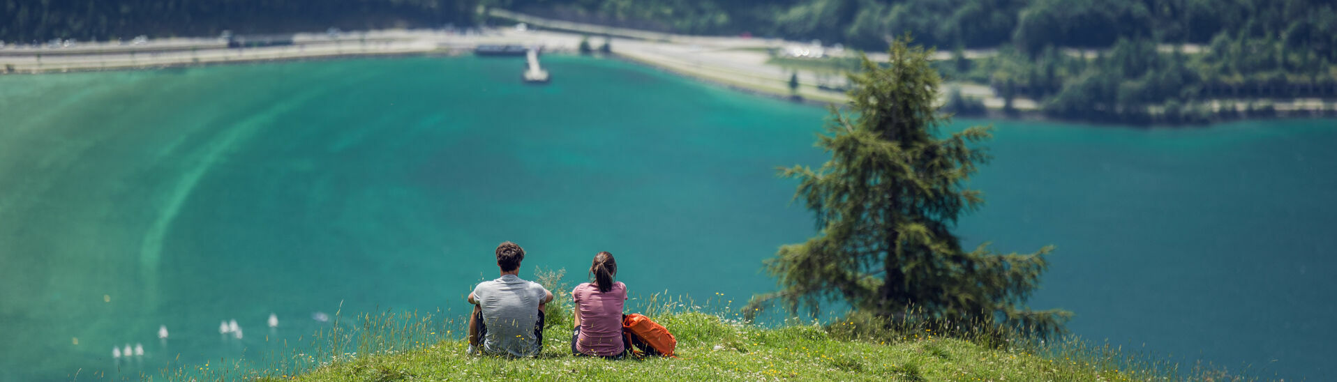 Ein Pärchen genießt den Ausblick auf den. türkis-blauen Achensee vom Rofangebirge aus.