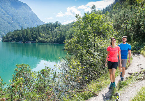 Ein Pärchen wandert am abenteuerlichen Gaisalmsteg neben dem Achensee, bei schönem Wetter.