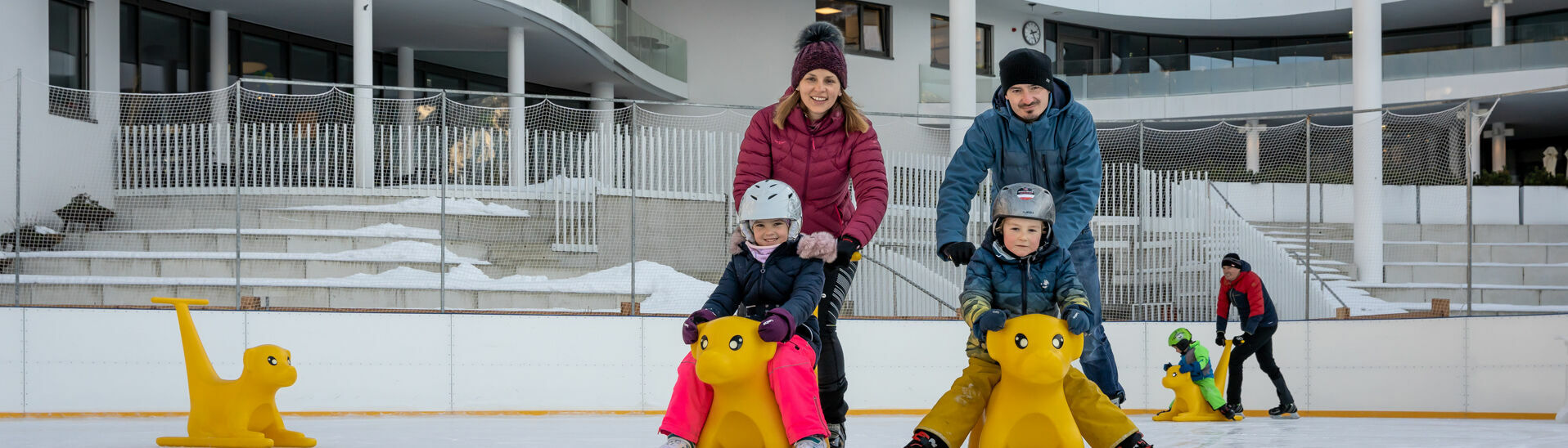 Eine Familie genießt den Wintertag auf dem Eislaufplatz des Atoll Achensee in Maurach.