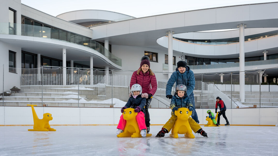 Eine Familie genießt den Wintertag auf dem Eislaufplatz des Atoll Achensee in Maurach.