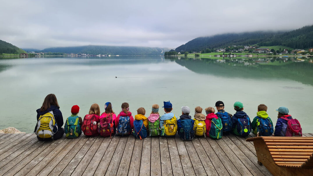 Ein Gruppe Kindergartenkinder blickt vom Steg auf den Achensee.