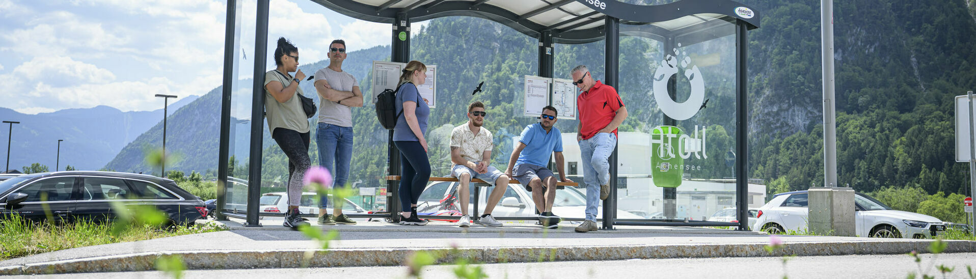 Eine Gruppe Männer und Frauen warten auf den nächsten Bus bei der Haltestelle des Atoll Achensee.
