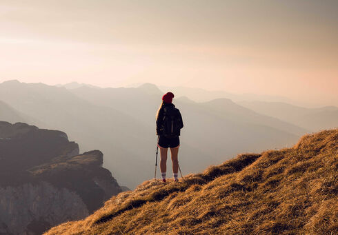 Ein Wanderer genießt die wunderschöne Aussicht vom Rofan bei rotem Himmel.