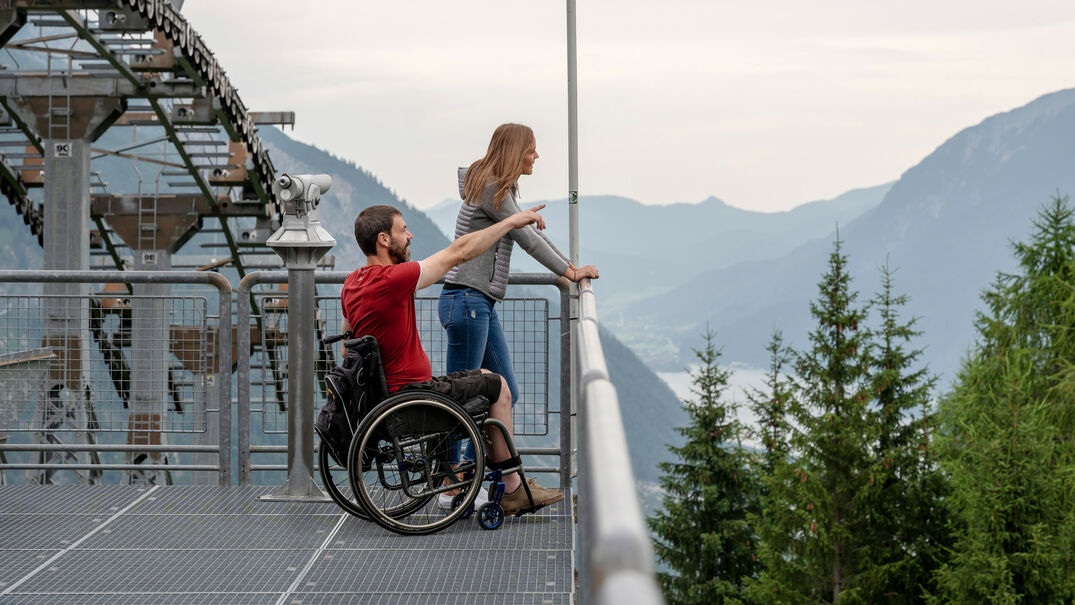 The Karwendel mountain railroad enables wheelchair users to enjoy a carefree ride in the mountains. Two friends enjoy the view of the Achensee region from the Zwölferkopf.