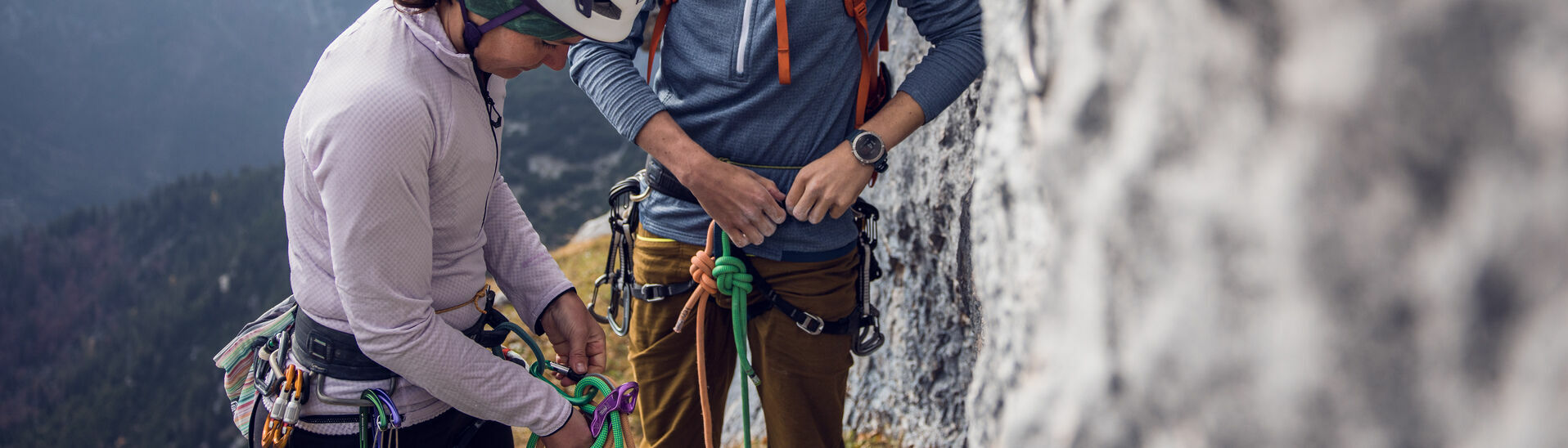 Zwei Personen checken ihre Sicherheitsausrüstung am Südgrat des Gufferts bei bewölktem Wetter.
