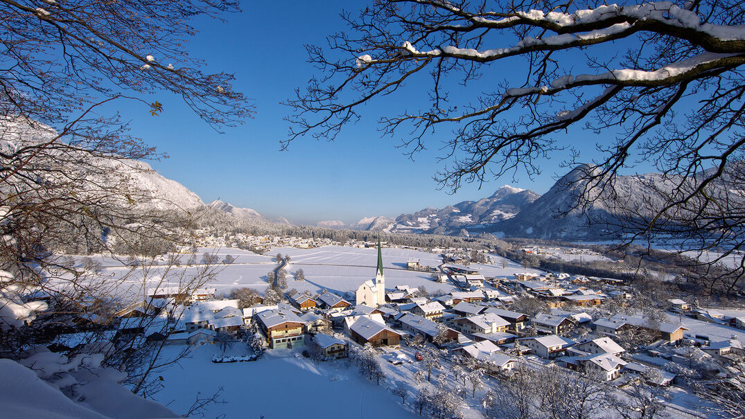 Eine Winteraufnahme vom Dorf Wiesing mit der Pfarrkirche Wiesing, welches im Inntal am Fuße der Achensee Region liegt.