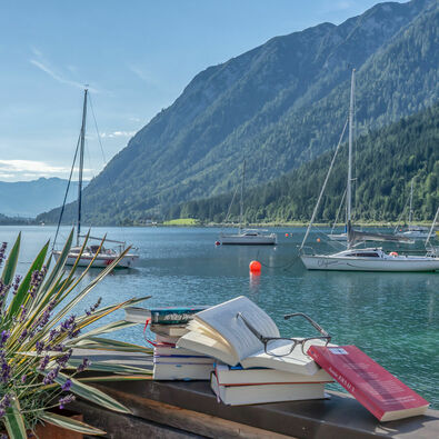 Im Zuge des Literaturfestivals „achensee.literatour“ wurden viele fesselnde Bücher vor einer atemberaubenden Kulisse in Szene gesetzt, begleitet vom malerischen Achensee, Segelbooten und dem majestätischen Ebner Joch im Hintergrund.