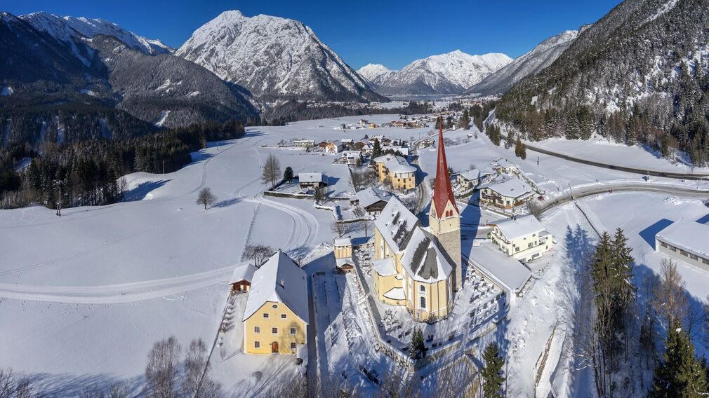 winterliche Ansicht von Eben und der Notburgakirche mit dem Notburga Museum (links von der Kirche)