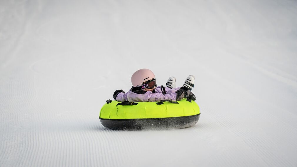 Zwei Kinder ziehen ihre Snowtubes durch den Schnee, bereit für die nächste Abfahrt.