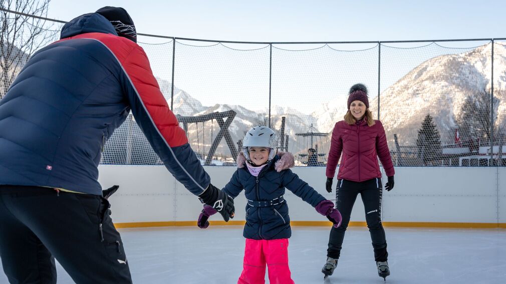Eine Familie genießt den Wintertag auf dem Eislaufplatz des Atoll Achensee in Maurach.