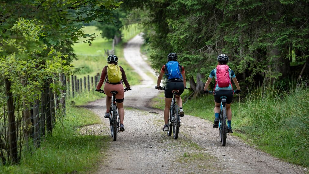 Zwei Mountainbikerinnen entspannen nach ihrer Tour zur Gufferthütte in Liegestühlen und genießen einen frisch servierten Kaiserschmarrn.