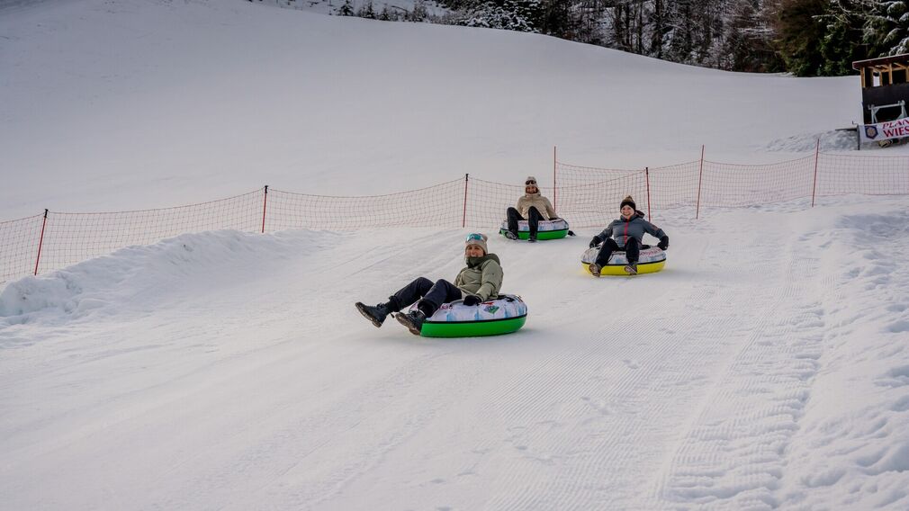 Zwei Kinder ziehen ihre Snowtubes durch den Schnee, bereit für die nächste Abfahrt.