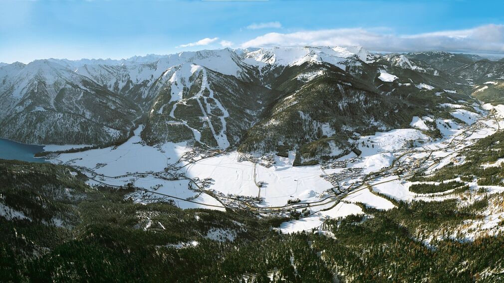 Winterliche Aufnahme vom Dorf Achenkirch am Achensee mit Blick auf das Skigebiet Hochalmlifte Christlum.