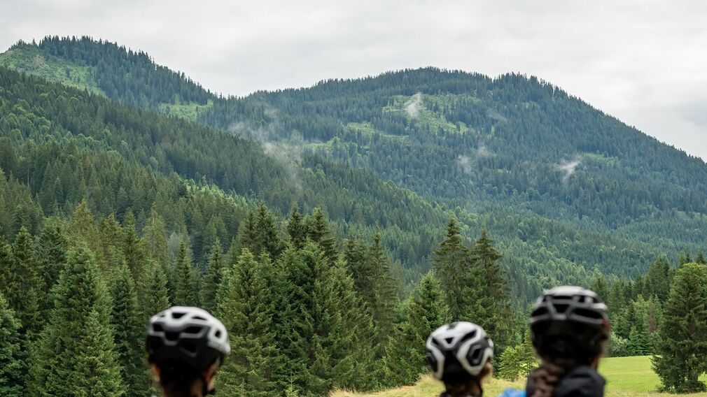 Zwei Mountainbikerinnen entspannen nach ihrer Tour zur Gufferthütte in Liegestühlen und genießen einen frisch servierten Kaiserschmarrn.