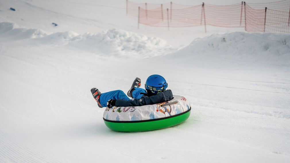 Zwei Kinder ziehen ihre Snowtubes durch den Schnee, bereit für die nächste Abfahrt.