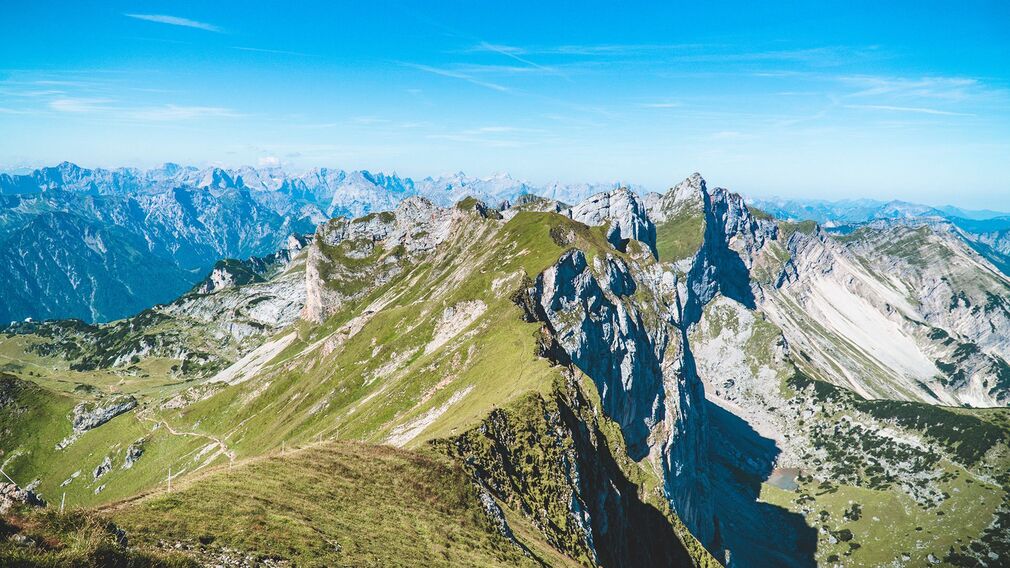 Ein Pärchen freut sich über den Gipfelsieg und genießt den Blick von der Rofanspitze auf die umliegende Berglandschaft.